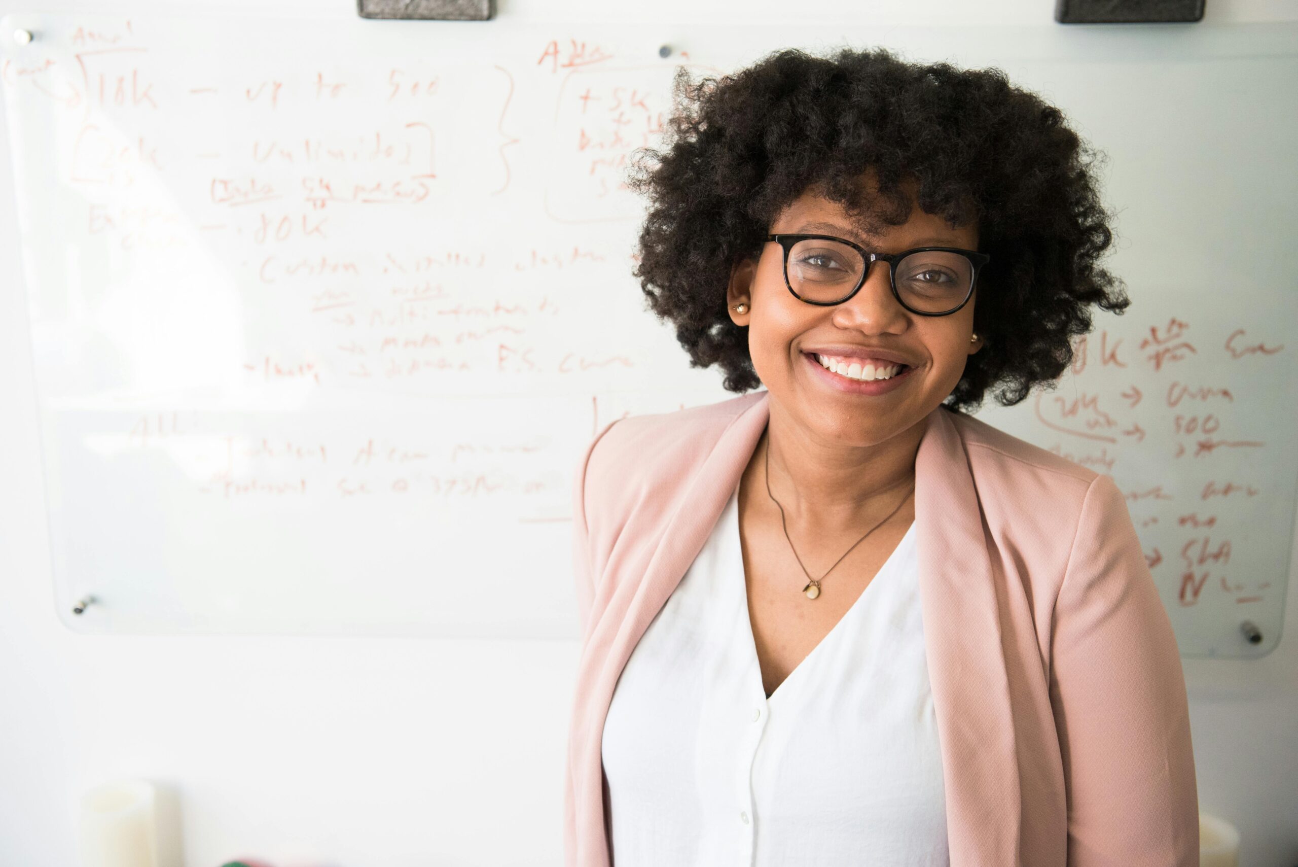 Home Smiling businesswoman with glasses and afro hairstyle in an office setting.